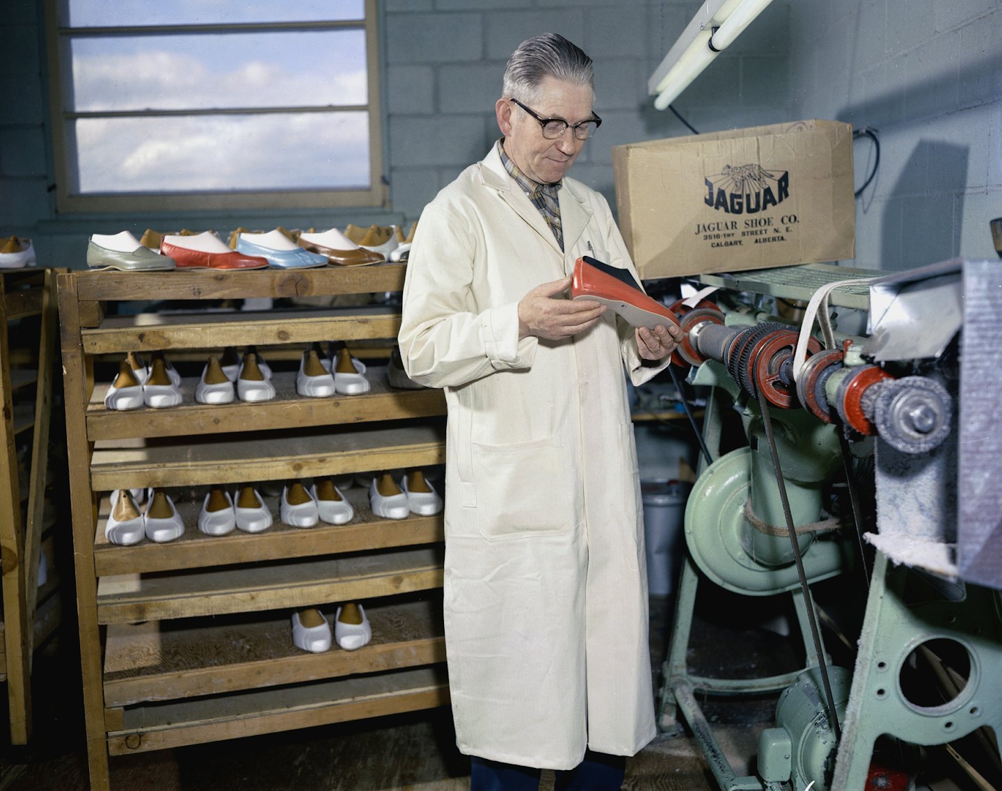 Tecnico in camice da laboratorio ispeziona la suola di una scarpa in fabbrica.